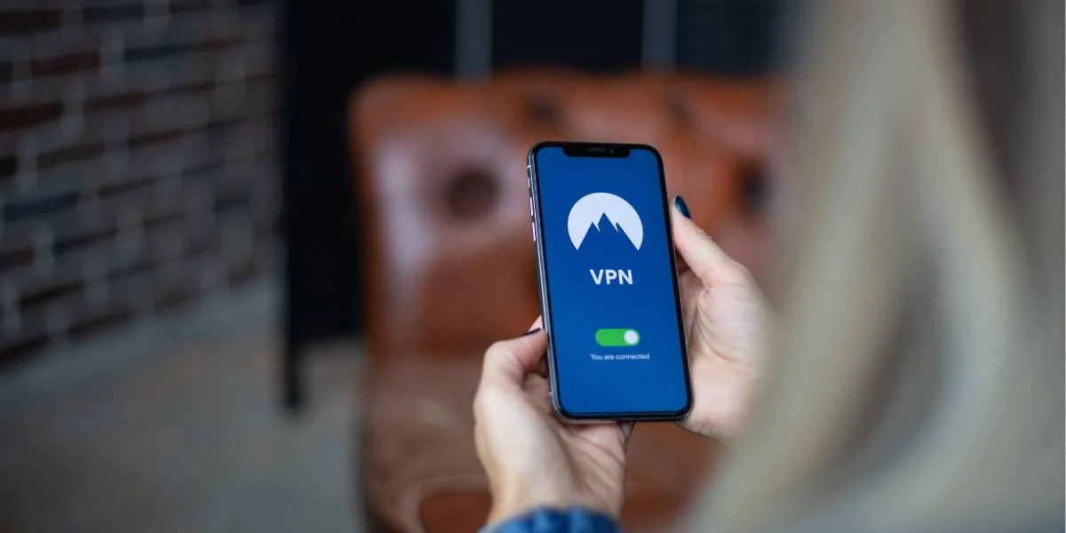 Nainen pitää kädessään älypuhelinta, jossa on auki NordVPN-sovellus.